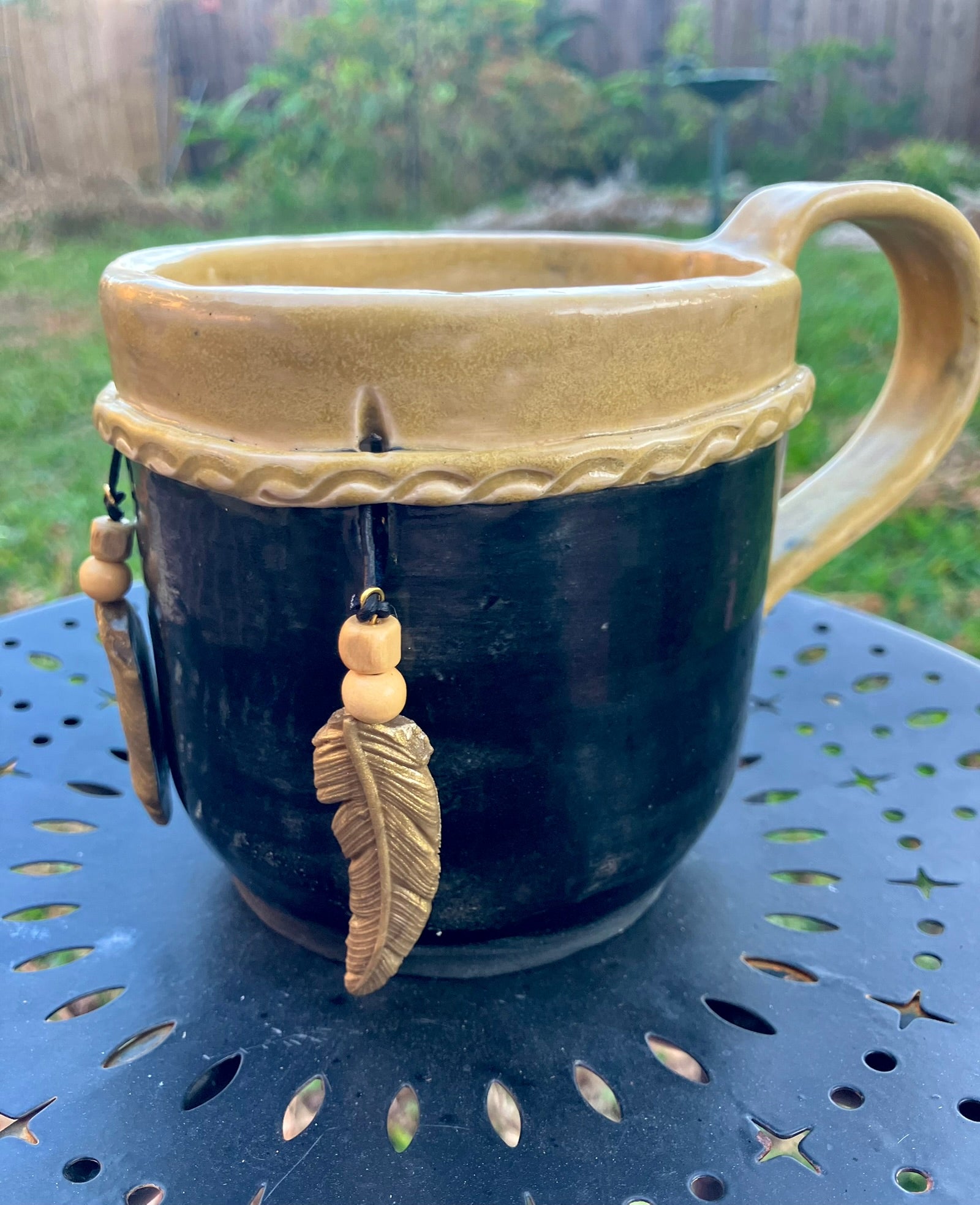 Handcrafted Dreamkeeper Mug with sculpted hanging feathers, Black & Gold glaze, and braided band detail, handmade pottery by Dhess Pottery