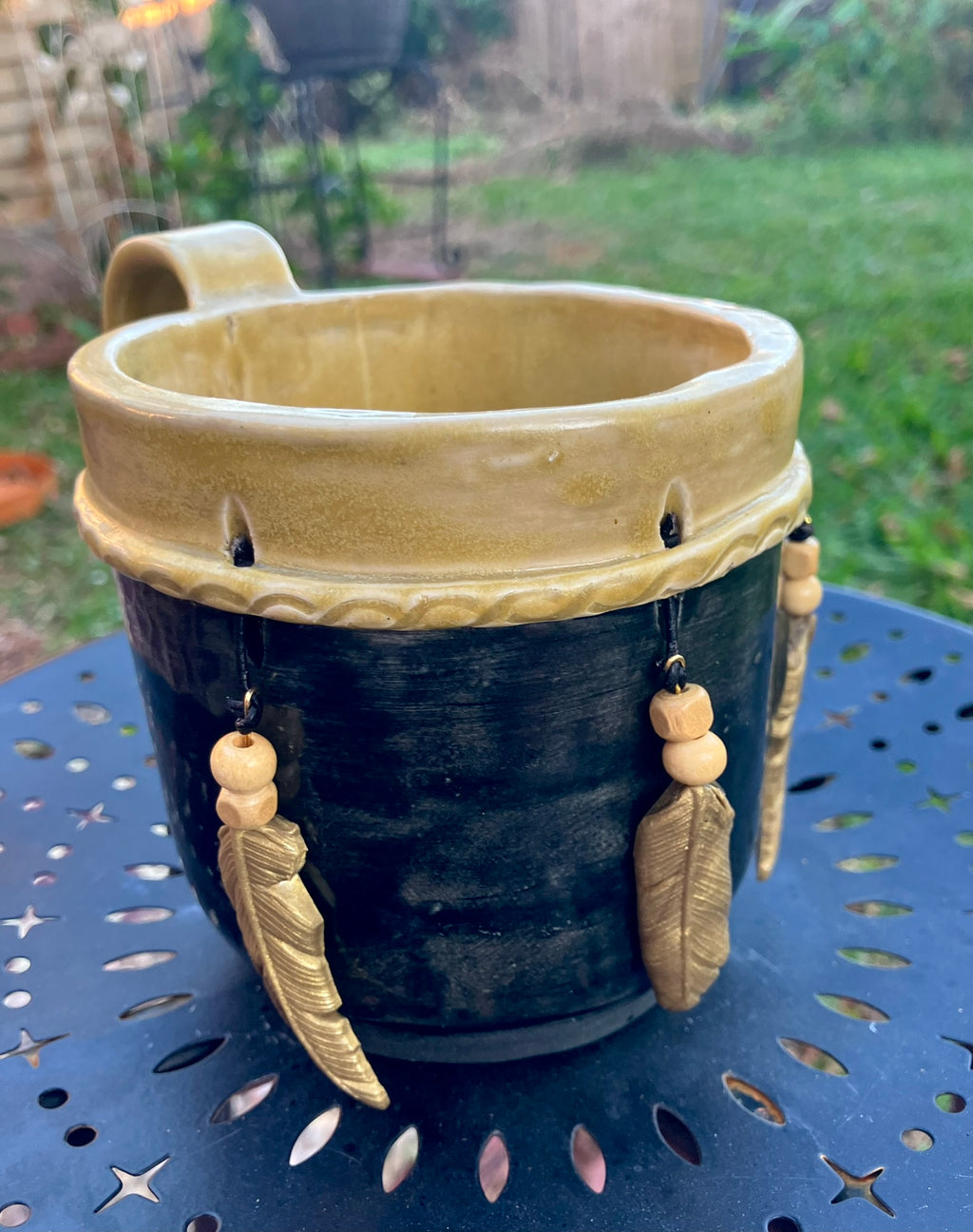 Handcrafted Dreamkeeper Mug with sculpted hanging feathers, Black & Gold glaze, and braided band detail, handmade pottery by Dhess Pottery