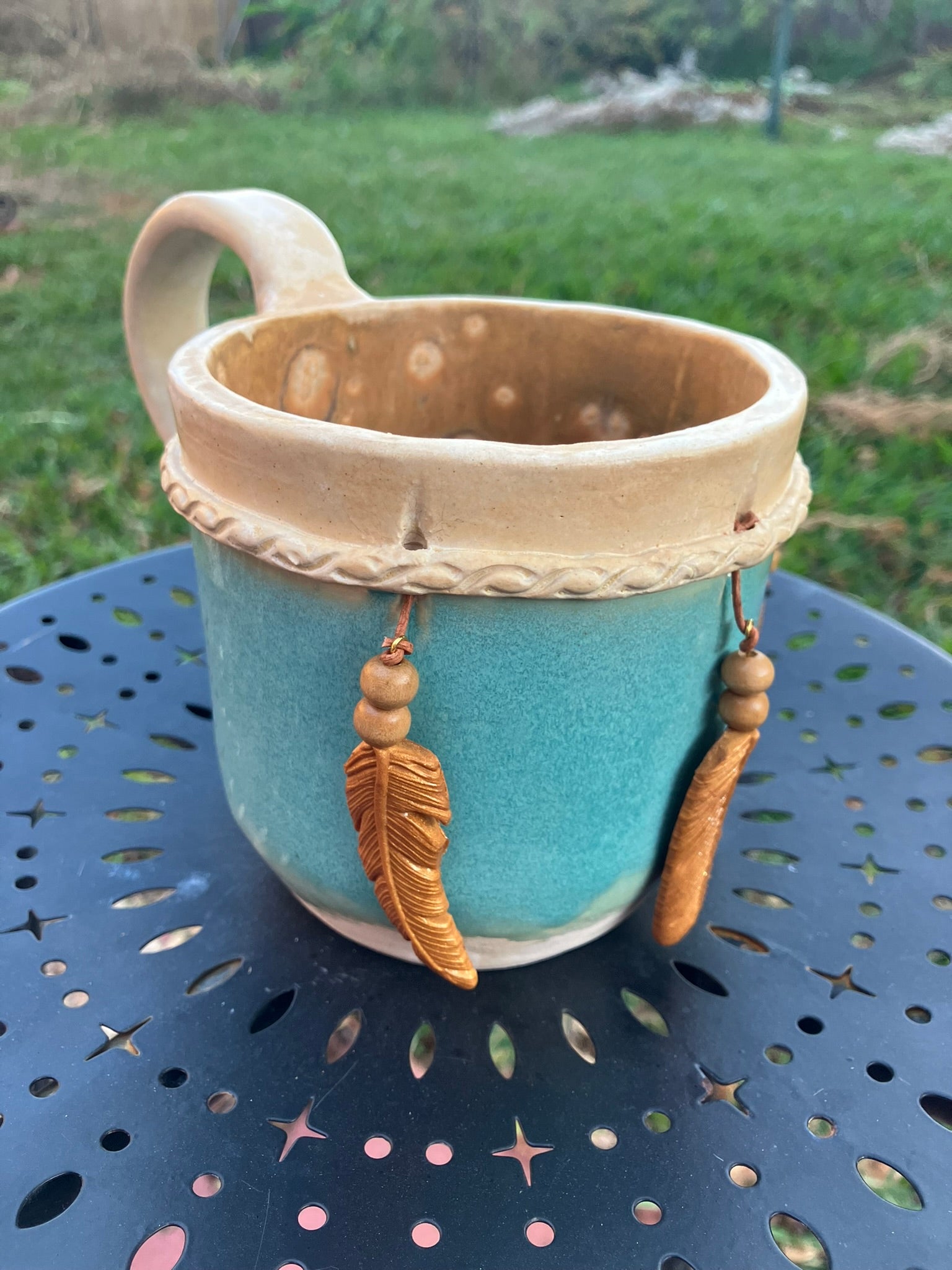 Handcrafted Dreamkeeper Mug with sculpted hanging feathers, Turquoise glaze, and braided band detail, handmade pottery by Dhess Pottery