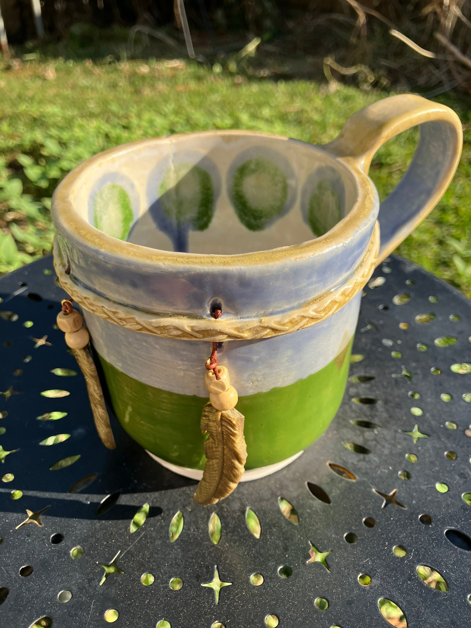 Handcrafted Dreamkeeper Mug with sculpted hanging feathers, blue & green glaze, and braided band detail, handmade pottery by Dhess Pottery