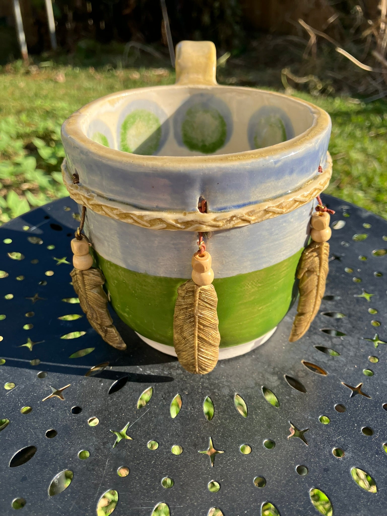Handcrafted Dreamkeeper Mug with sculpted hanging feathers, blue & green glaze, and braided band detail, handmade pottery by Dhess Pottery