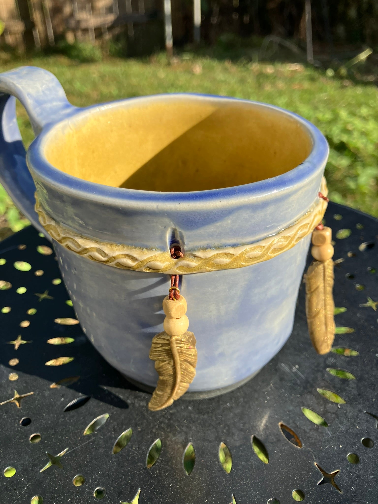 Handcrafted Dreamkeeper Mug with sculpted hanging feathers, blue sky glaze, and braided band detail, handmade pottery by Dhess Pottery