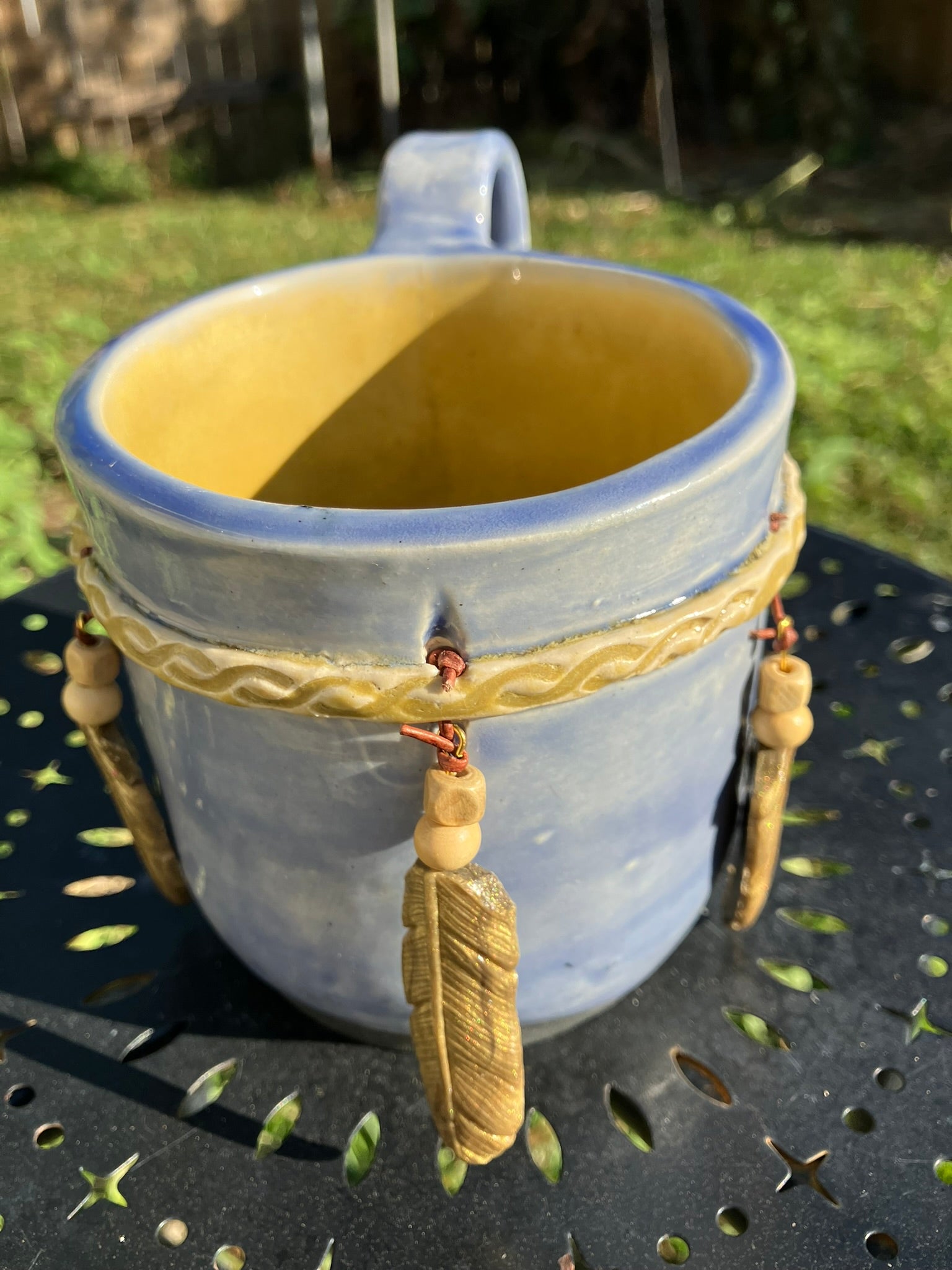 Handcrafted Dreamkeeper Mug with sculpted hanging feathers, blue sky glaze, and braided band detail, handmade pottery by Dhess Pottery