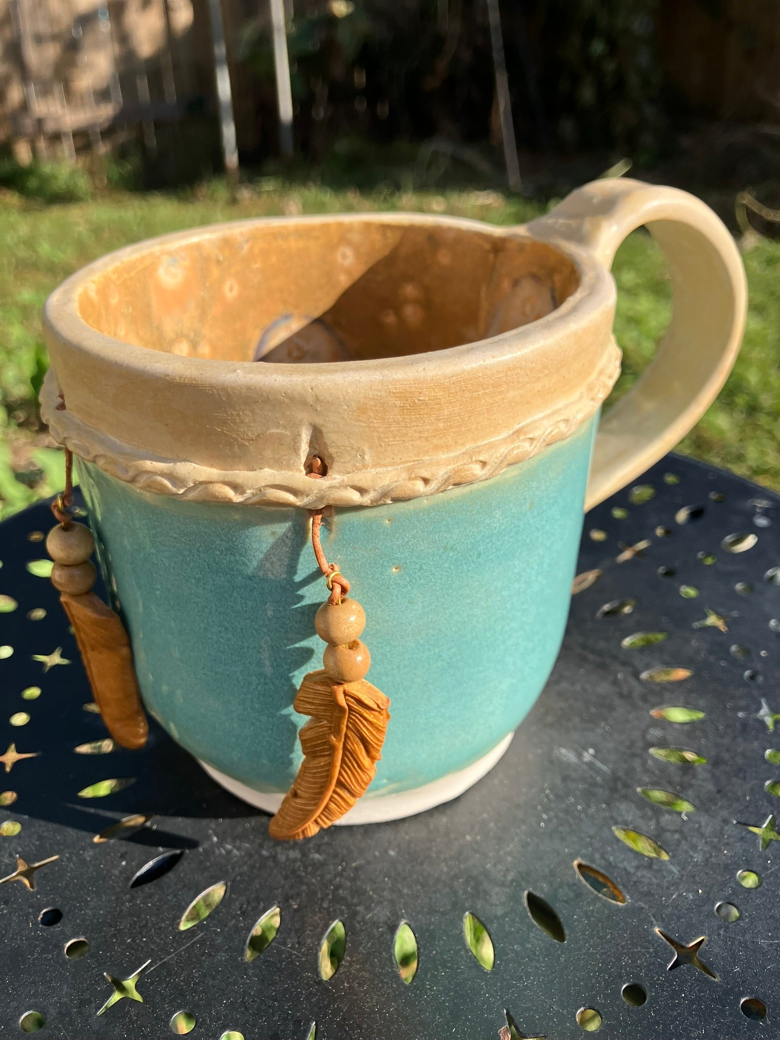 Handcrafted Dreamkeeper Mug with sculpted hanging feathers, Turquoise glaze, and braided band detail, handmade pottery by Dhess Pottery