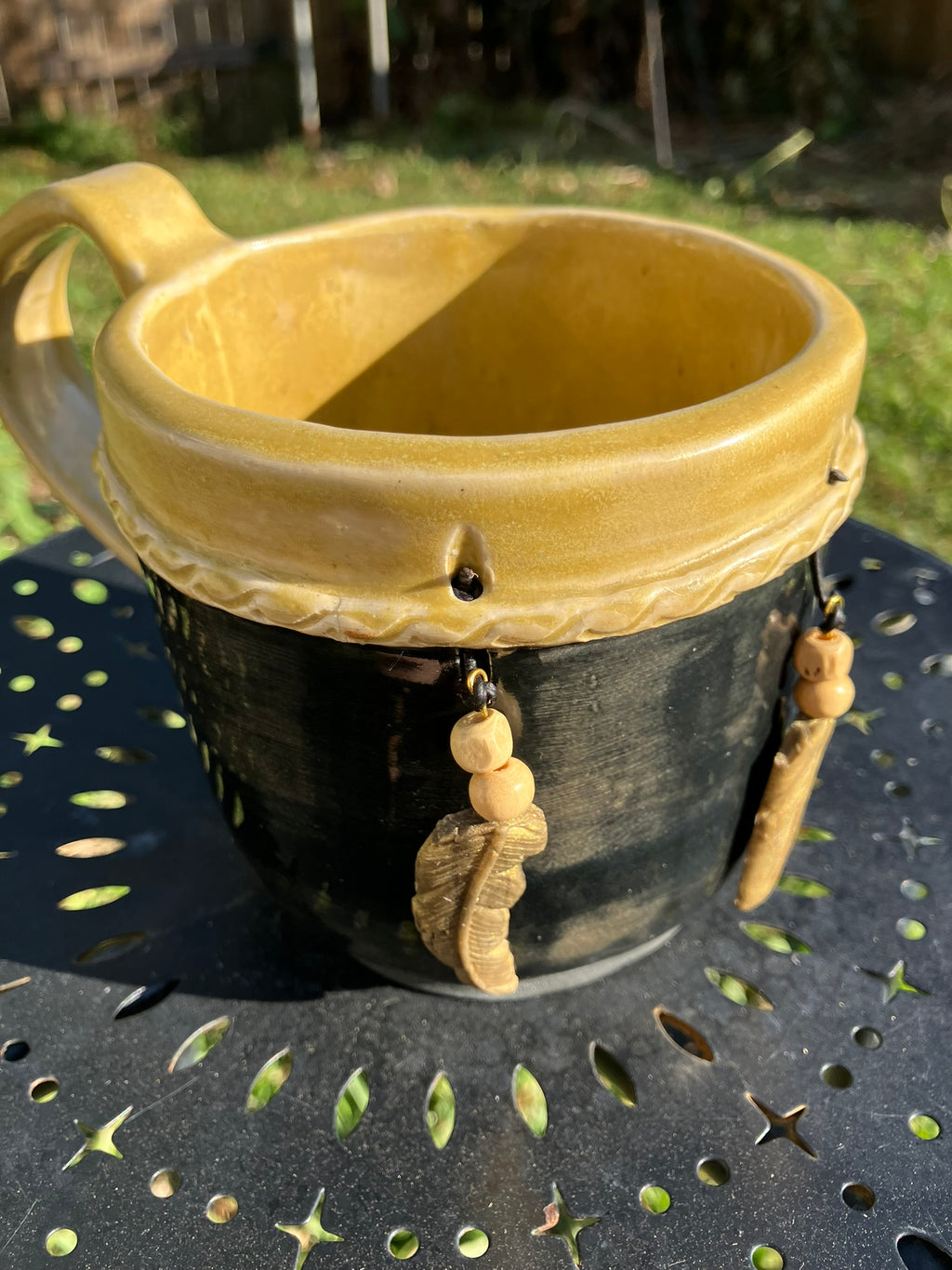 Handcrafted Dreamkeeper Mug with sculpted hanging feathers, Black & Gold glaze, and braided band detail, handmade pottery by Dhess Pottery