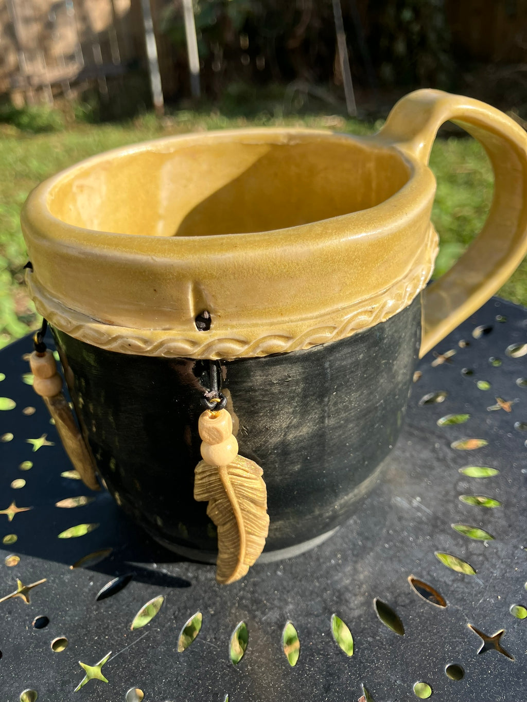 Handcrafted Dreamkeeper Mug with sculpted hanging feathers, Black & Gold glaze, and braided band detail, handmade pottery by Dhess Pottery