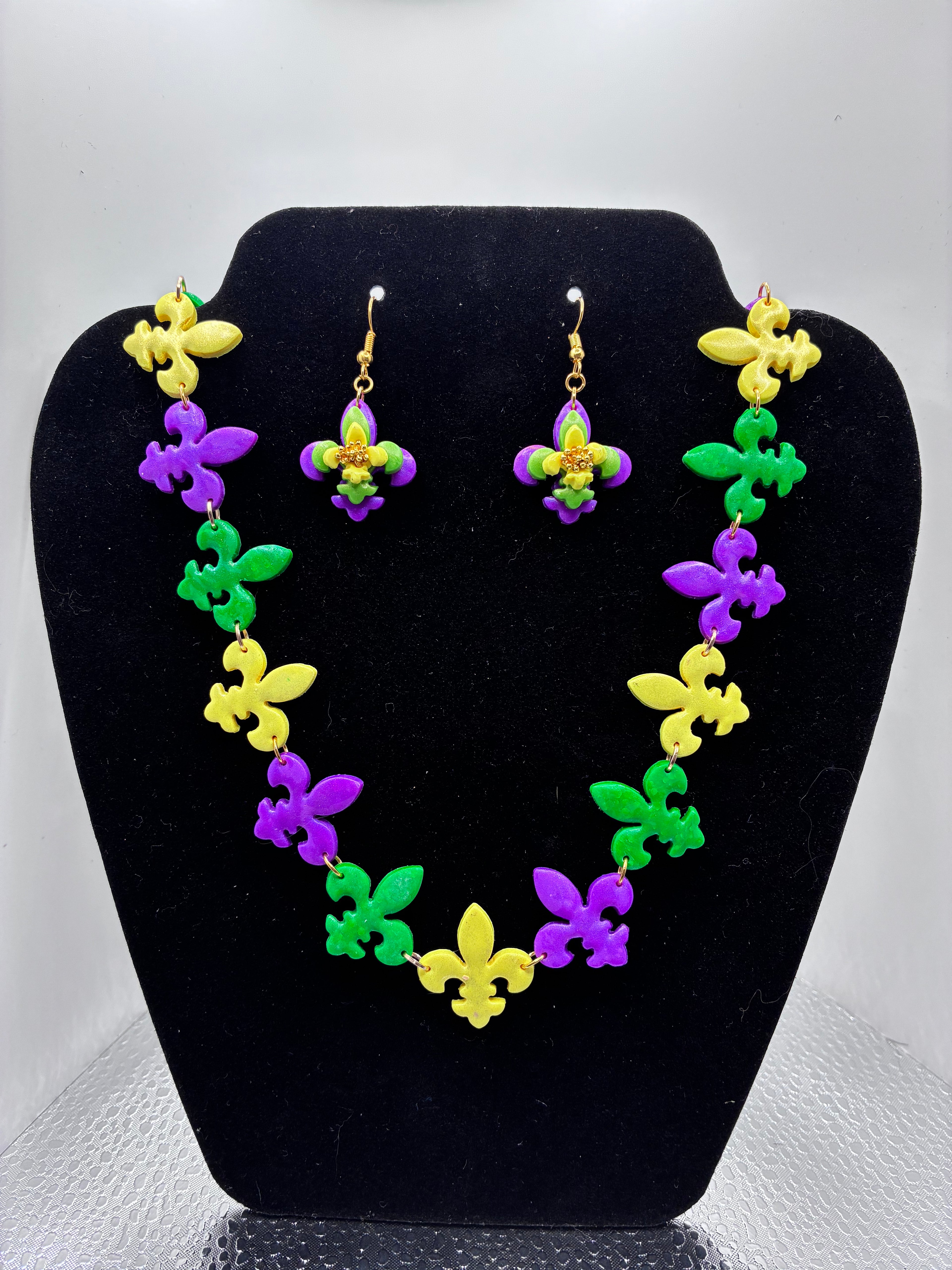 Colorful necklace and earrings set on a black stand with a white background