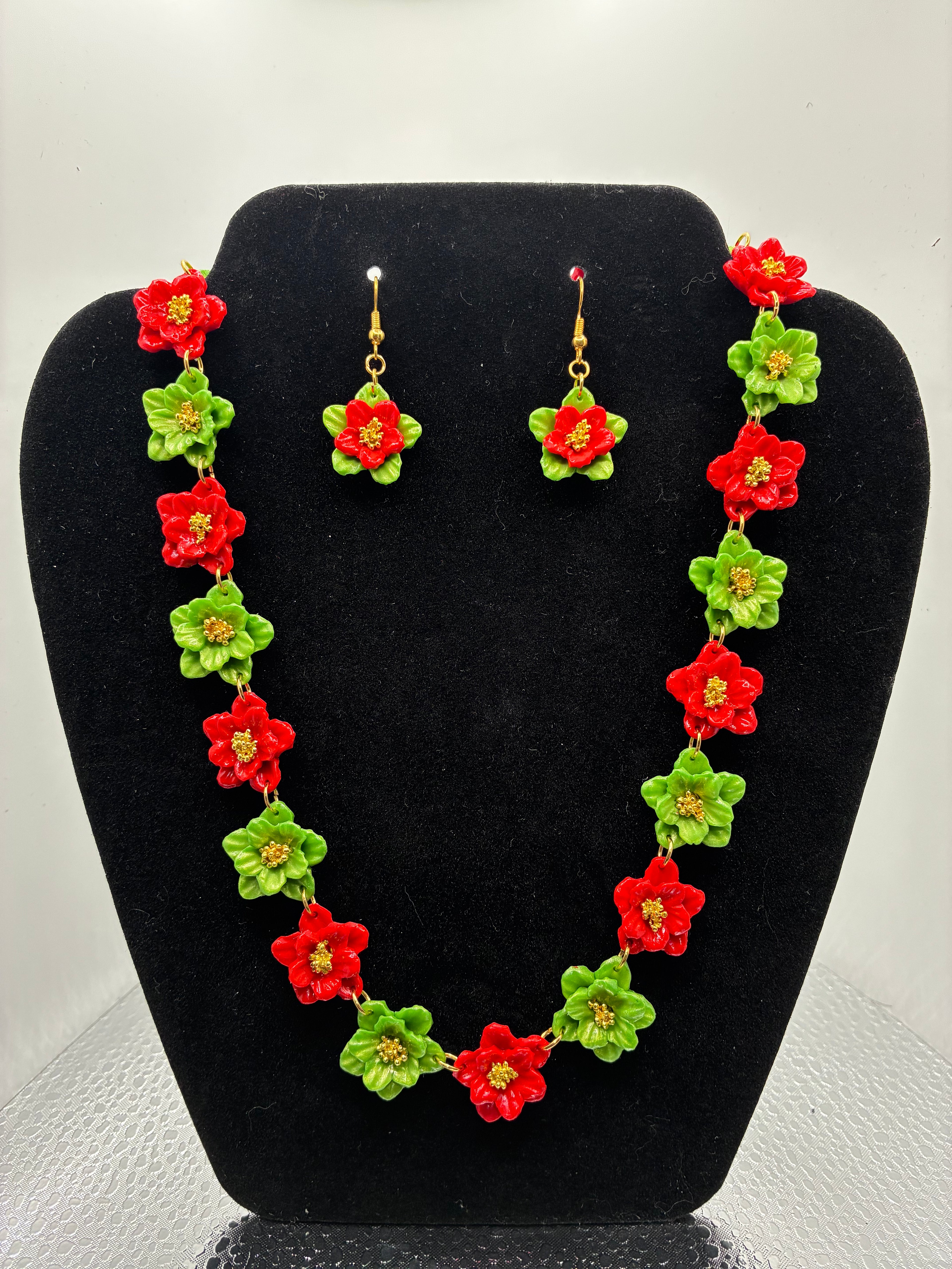 Floral necklace and earrings set on a black stand against a white background