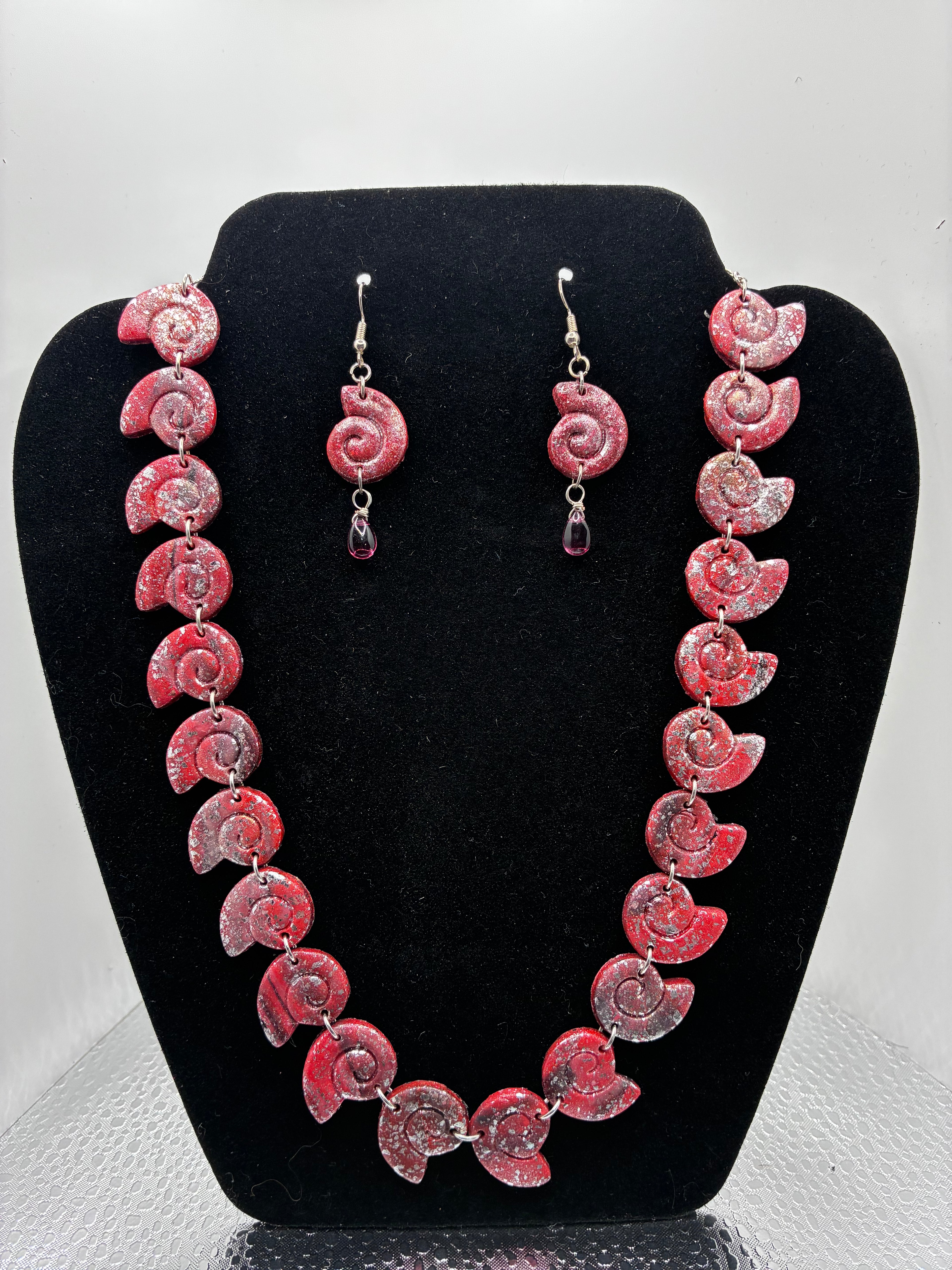 Set of pink jewelry on a black display stand against a white background