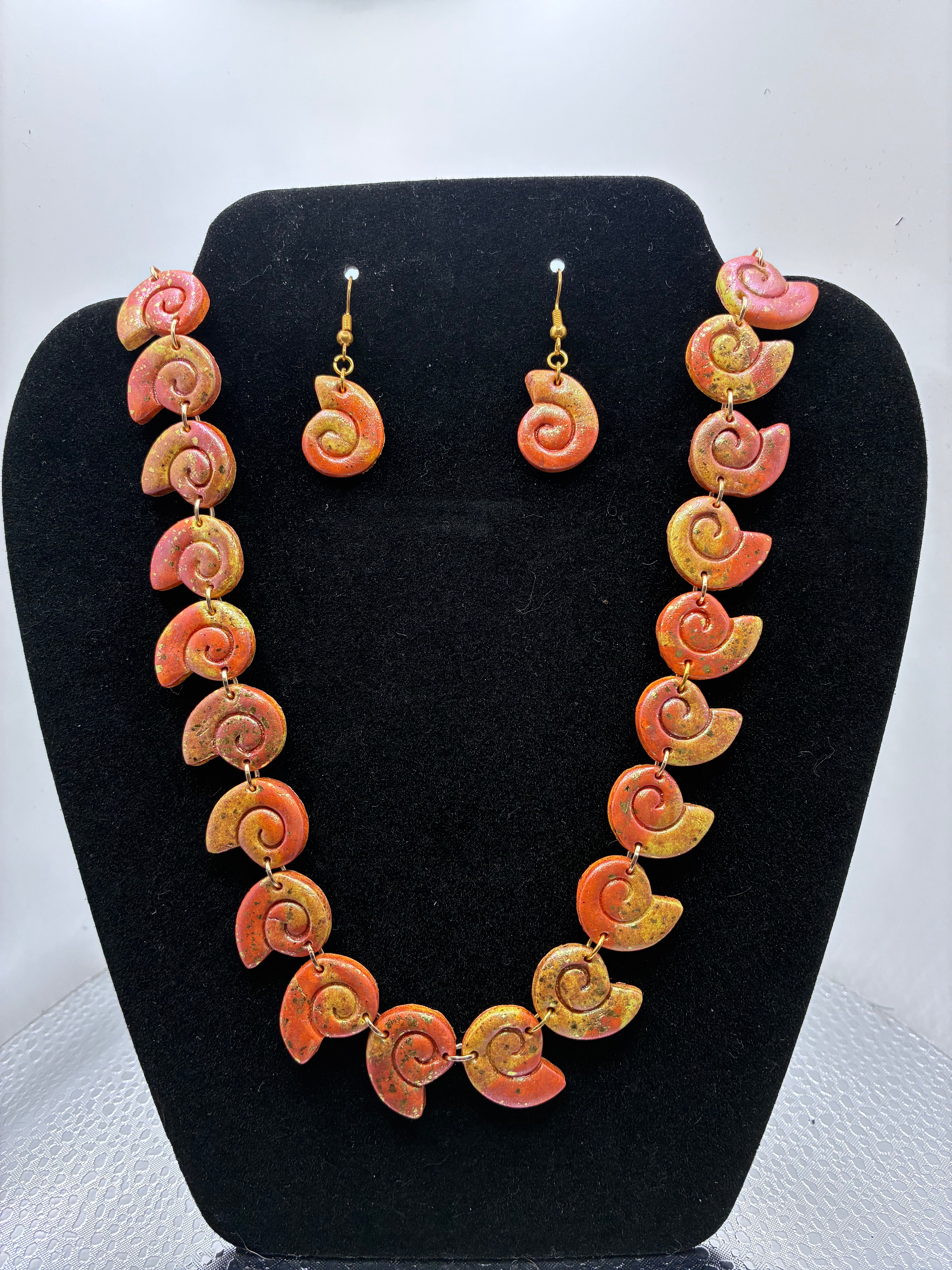 Necklace and earrings set on a black stand with a white background
