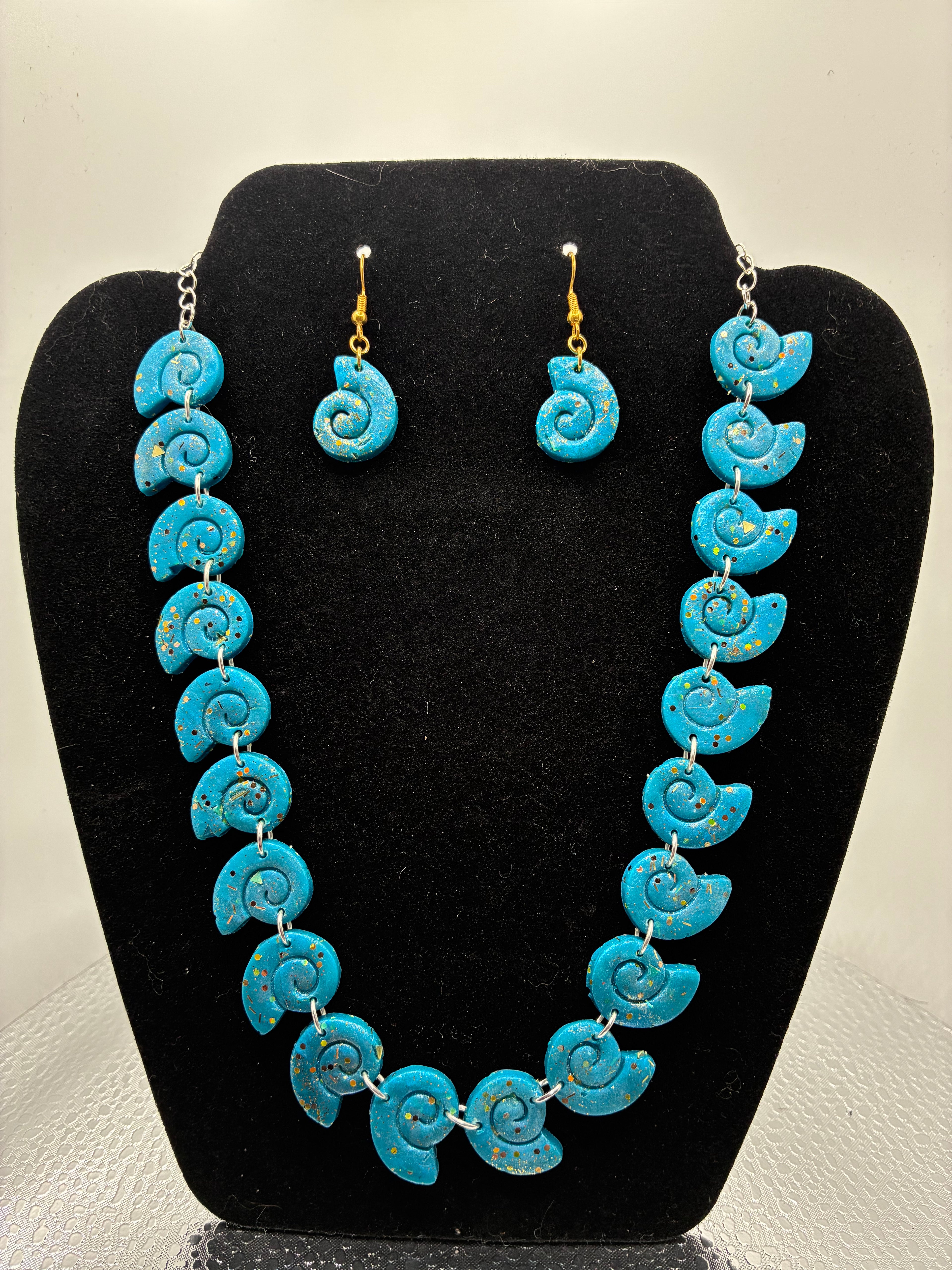 Turquoise spiral necklace and earrings set on a black stand.
