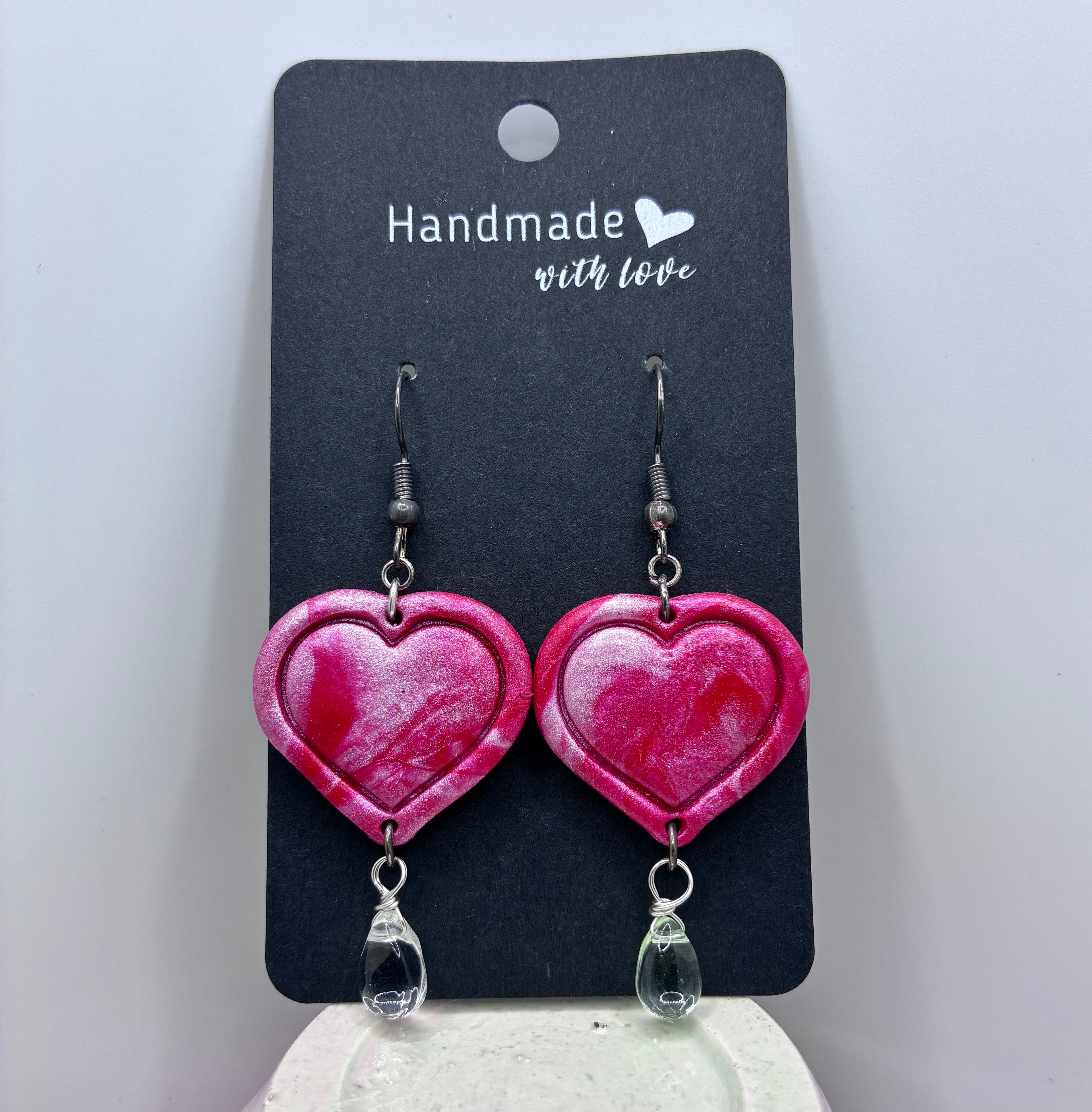 Heart-shaped earrings on a 'Handmade with Love' card against a white background