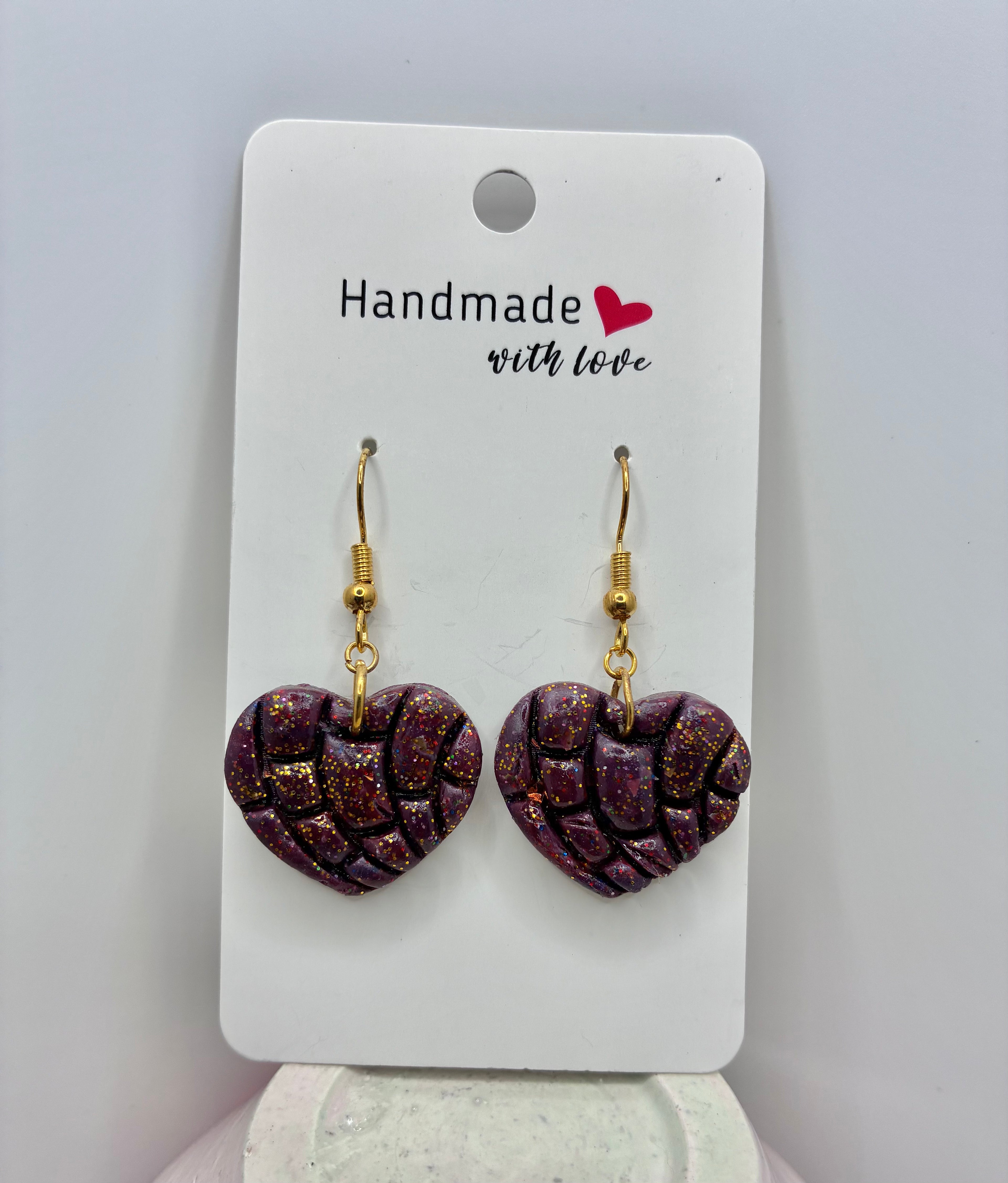 Heart-shaped earrings on a 'Handmade with Love' card against a gray background