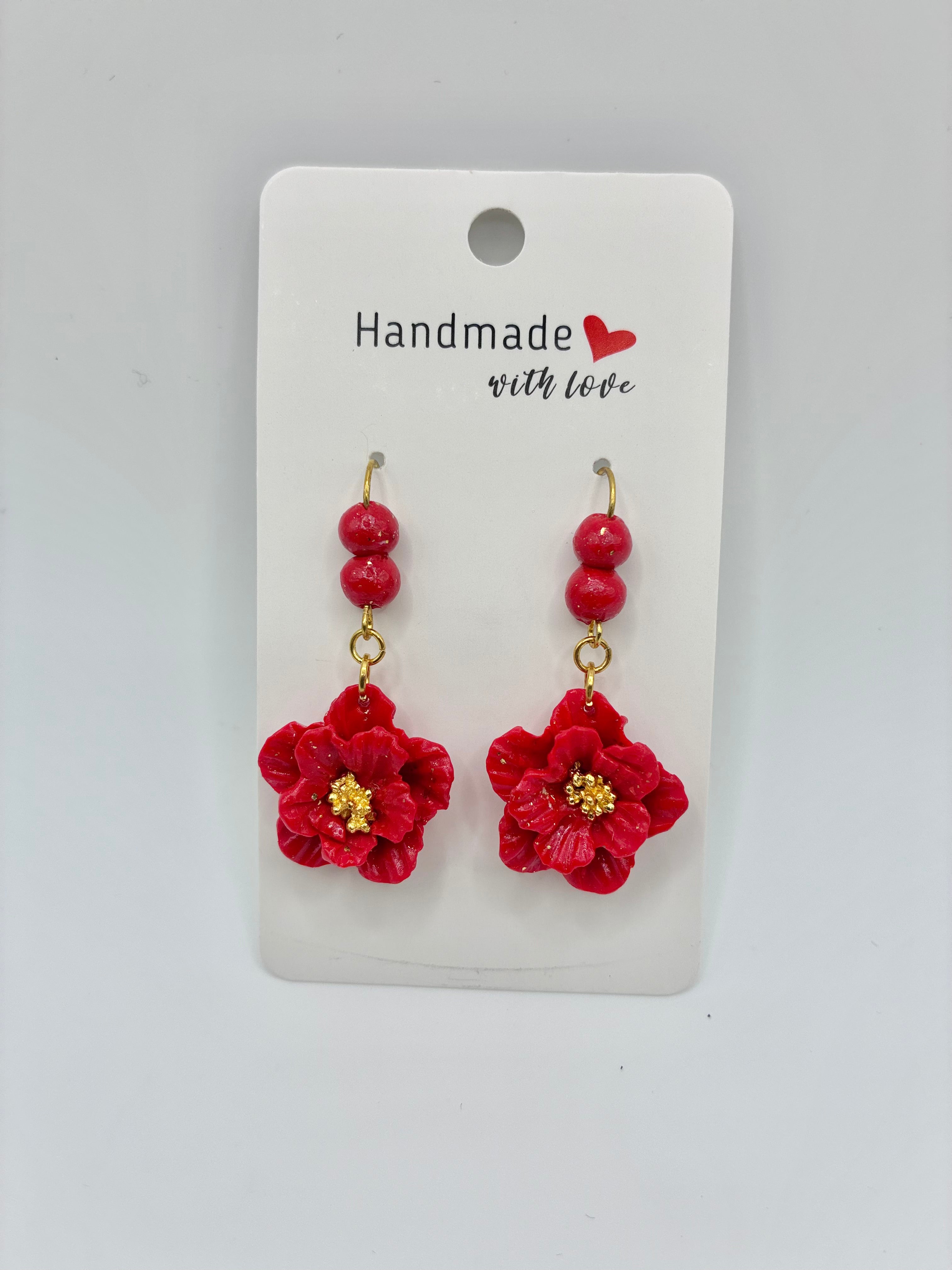 Red floral earrings on a 'Handmade with Love' card against a gray background