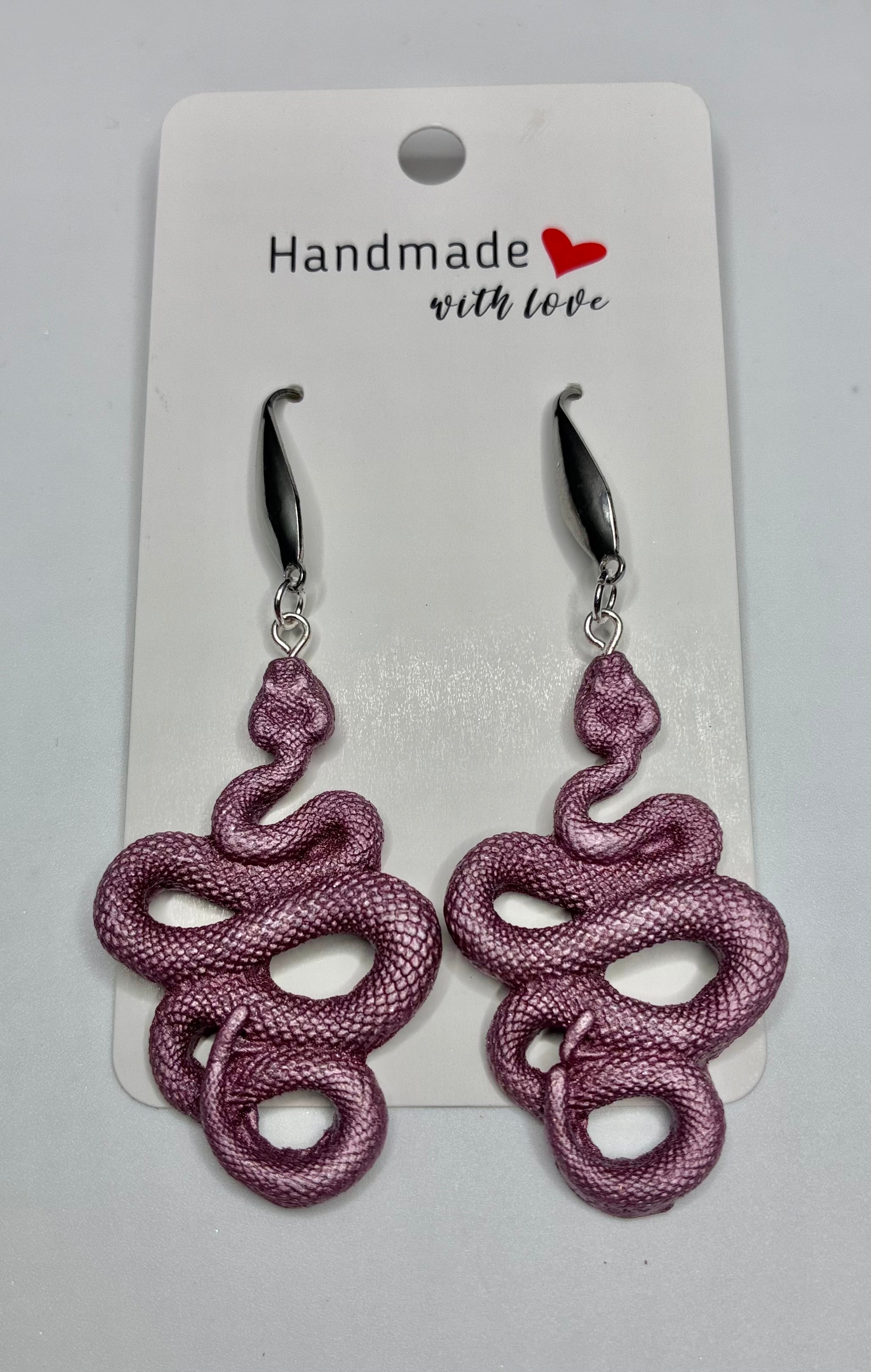 Purple snake-shaped earrings on a 'Handmade with Love' card.