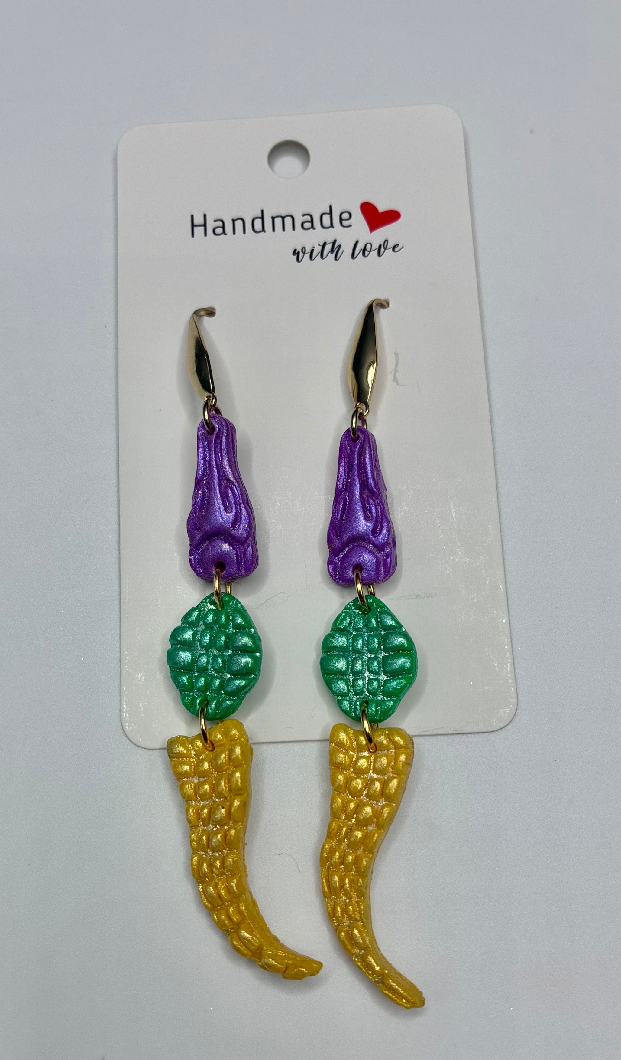Pair of earrings with purple, green, and gold colors on a 'Handmade with Love' card.